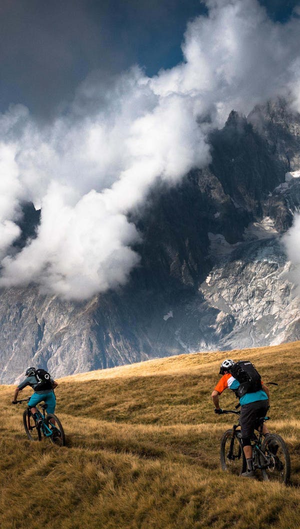 Two mountain bikers riding down alpine terrain