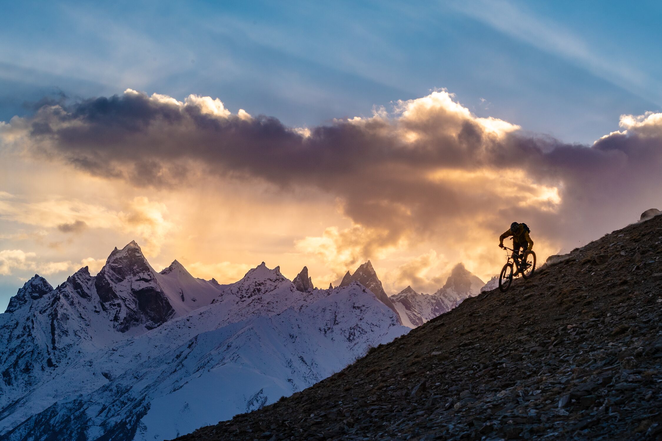 Carston Oliver riding a ridgeline with a beautiful sunset in the background