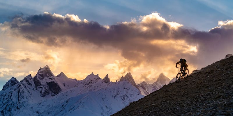 Carston Oliver riding a ridgeline with a beautiful sunset in the background