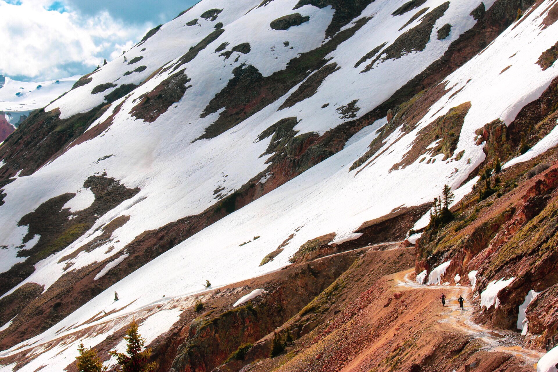 Riders traversing a high alpine road. 