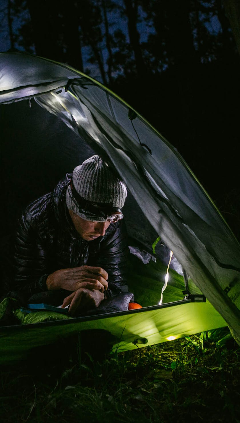 Justin Reiter settling into a illuminated tent off the Colorado Trail for the night